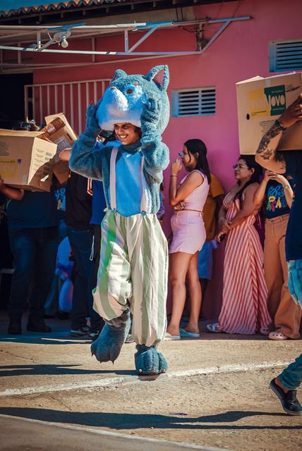 Voluntário fantasiado de lobo azul entre famílias na fila da ação